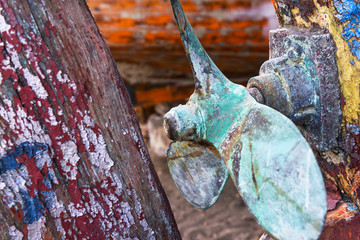 Rusty and green ship propeller on a colorful background