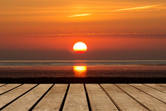 leere Holzboden Bretter vor einer aufgehenden Sonne über dem Meer