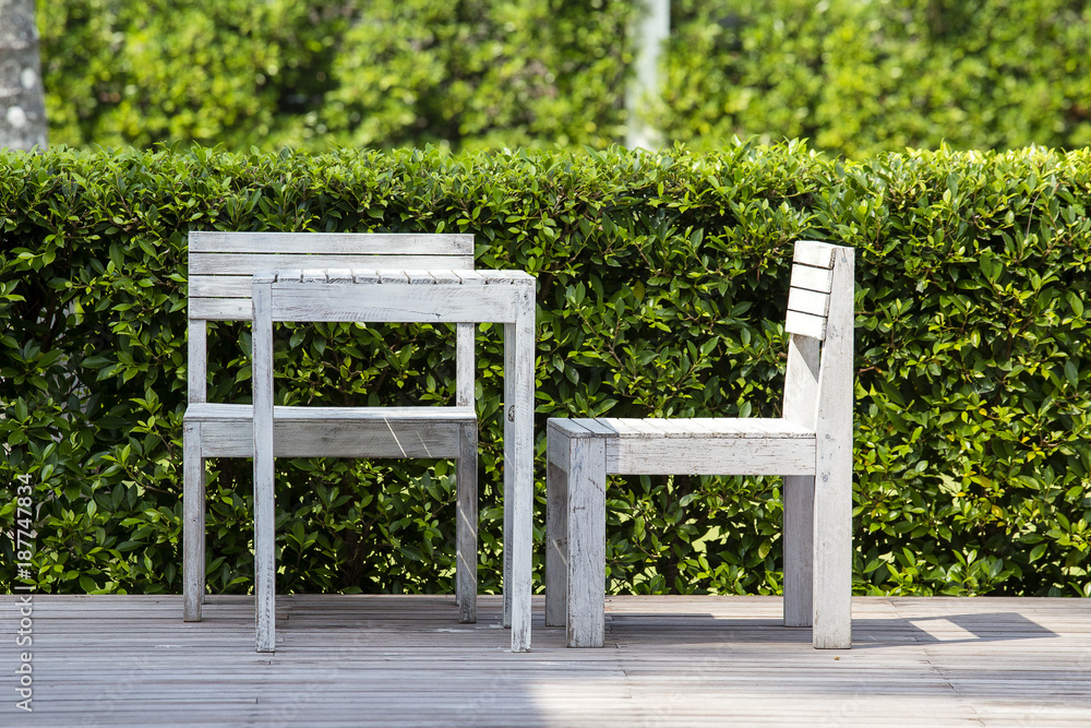 Wall mural wooden two chairs and white table in empty cafe of a tropical garden on the beach, thailand. close u