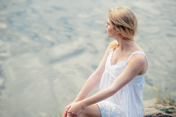 Fototapeta na wymiar Dreaming girl wearing light white dress on the beach