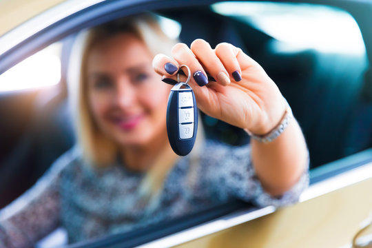 Happy woman driver holding auto keys in her car