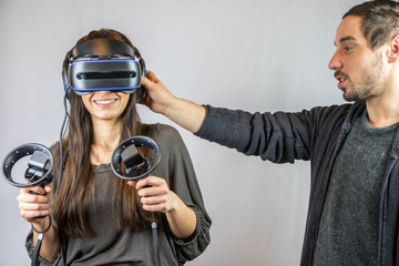 Junge Frau spielt mit Virtual Reality Datenbrille, ungeduldiger Freund zerrt an Headseat
