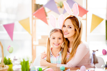 Obraz na płótnie Canvas Charming, attractive, pretty mother and daughter preparing for Easter, hugging, smiling looking at camera, spending time together, wearing bunny ears, rabbit costume