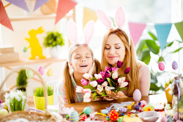 Obraz na płótnie Canvas Mother and daughter relaxing on Easter holiday, holding bouquet of colorful tulips, smelling with close eyes, having comfort, pleasure