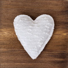 Picture of beautiful handmade white heart on vintage wooden background, soft heart toy. White cloth heart.  Top view. Love concept for Valentine’s day.