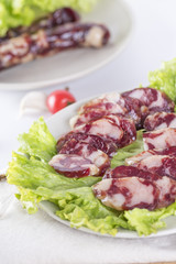 Close-up of cold cuts and vegetables on a plate. Raw pork sausage.