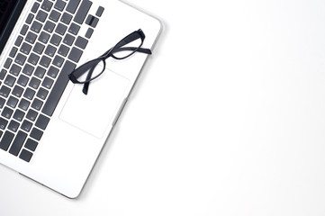 Naklejka premium laptop computer and black glasses on white background with copy space 