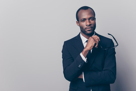 Portrait of confident discerning self-affured chief on a company dressed in black jacket and white shirt holding glasses in hand, isolated on gray background, copy-space