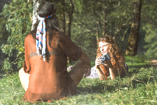 Pretty free hippie girls on the grass taking photos with an old - Vintage effect photo