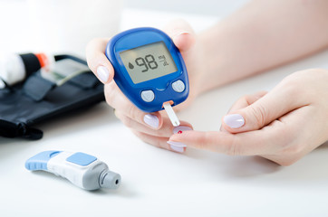 Woman checking blood sugar level by glucometer