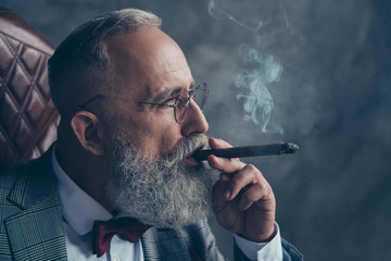 Side view close up of brutal harsh professional investor, shareholder smoking cigar over gray...