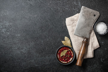Cooking background with vintage butcher cleaver and spices on blackboard