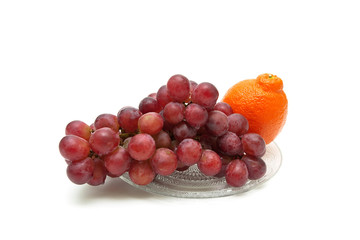 Dark grapes and orange on a white background.