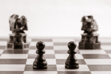 Classic black pawns and the same chess pieces in the form of medieval figure on the background