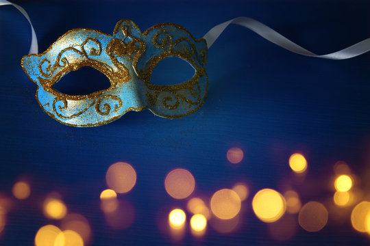 Image of elegant blue and gold venetian, mardi gras mask over blue background.