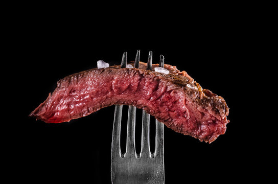 Beef meat rare on fork black background