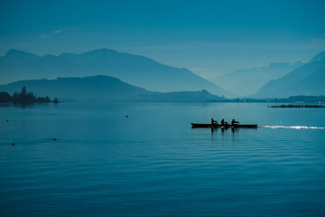 Kayakers crossing the Upper Lake Zurich inb the morning mist near Rapperswil, Sankt Gallen, Switzerland