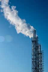 three smoking pipes against the blue sky. The concept of environmental pollution.