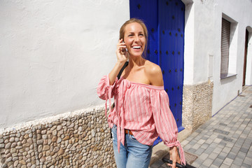 Happy young woman walking and talking on cellphone