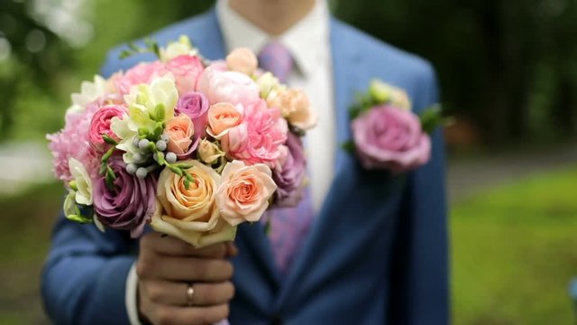 The man is holding a beautiful bouquet.