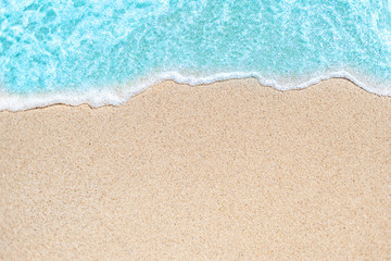 Background image of Soft wave of blue ocean on sandy beach.  Ocean wave close up with copy space for text. - obrazy, fototapety, plakaty