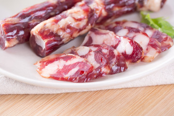 Close-up of cold cuts and vegetables on a plate. Raw pork sausage.