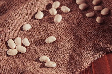 Navy bean or White bean on wooden background on burlap