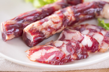 Close-up of cold cuts and vegetables on a plate. Raw pork sausage.