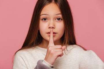 Calm beautiful girl looking camera andmaking silence gesture isolated