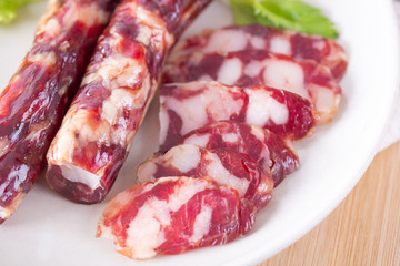 Close-up of cold cuts and vegetables on a plate. Raw pork sausage.