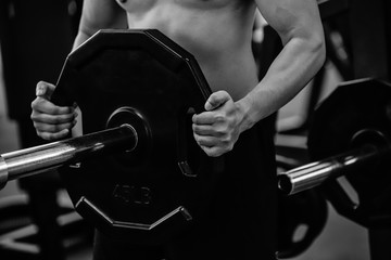 Male hand choosing a weight on a metal weights of bodybuilding equipment in a gym.