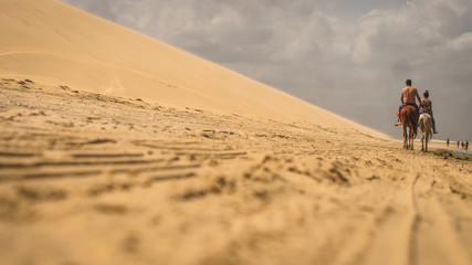 Fototapeta na wymiar horse riding in sand dunes at the beach
