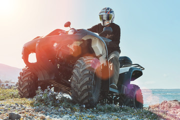 A man is driving ATV on off-road. Sunny.