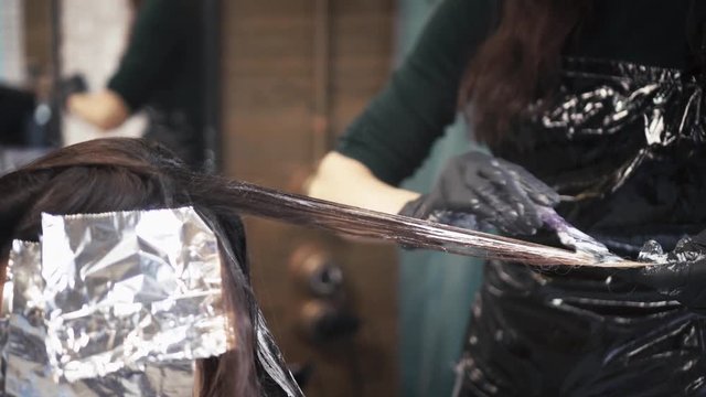 The hairdresser applies the pigment to the hair. Close-up.
