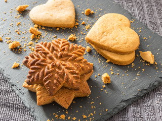 Yellow ginger biscuits in the shape of snowflakes and hearts on a black background