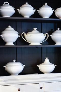 White porcelain soup tureens in kitchen cabinet