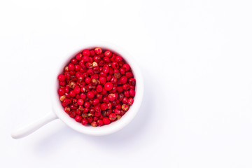 Organic Pink Peppercorn in white ceramic cup on white background with copy space