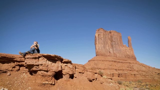 woman sitting on a rock with camera enjoying the landscape in Arizona.