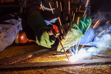 Welder perform welding to the metal plate at roof floor of manufacturing factory by using steel welding electrode in offshore oil and gas industrial operation, Blue collar jobs