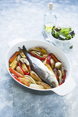Whole sea fish cooked in casserole dish with vegetables.