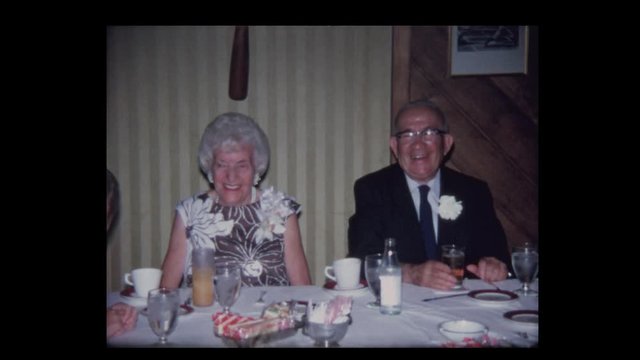 1968 Elderly couple at head table for anniversary party