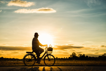 Obraz na płótnie Canvas Silhouette woman cycling at sunset