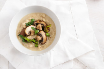Parsnip mash with roasted mushrooms and leek in a bowl on a white tablecloth,  healthy eating and slimming diet from vegetables, high angle view from above, copy space in the background