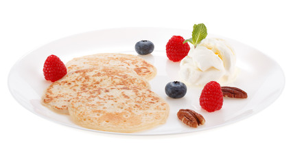 Serving pancakes with ice cream, nuts and fresh berries on the plate. Isolated on white background.