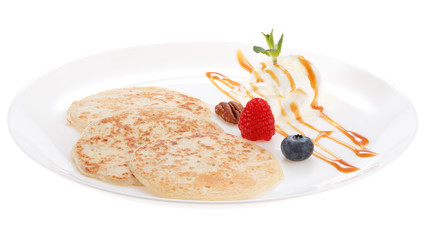 Serving pancakes with ice cream, nuts and fresh berries on the plate. Decorated with caramel syrup....