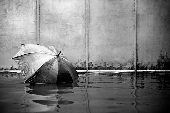 Concept of umbrella floating on flooded street with black and white colors and waiting for help me after the rain.