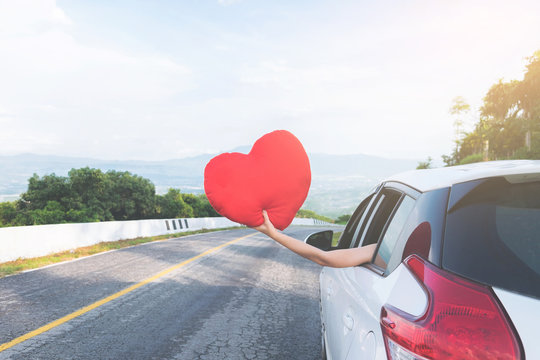 Young Asian Girl Holding Red Heart And Reach Out Of The Car At Sunset