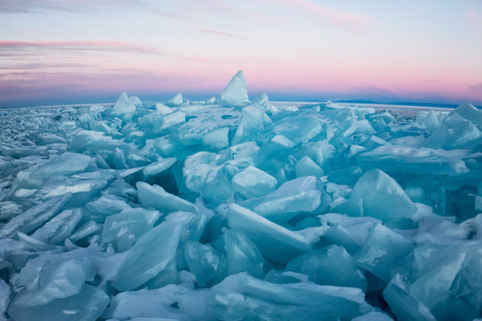Pure transparent ice of Lake Baikal through the sun is shining in the sunset