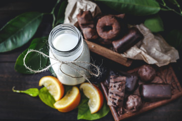 Milk in glass jar with orange and chocolate sweets, selective focus.