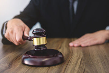 Male lawyer or judge hand's striking the gavel on sounding block, working at courtroom, Law and justice concept